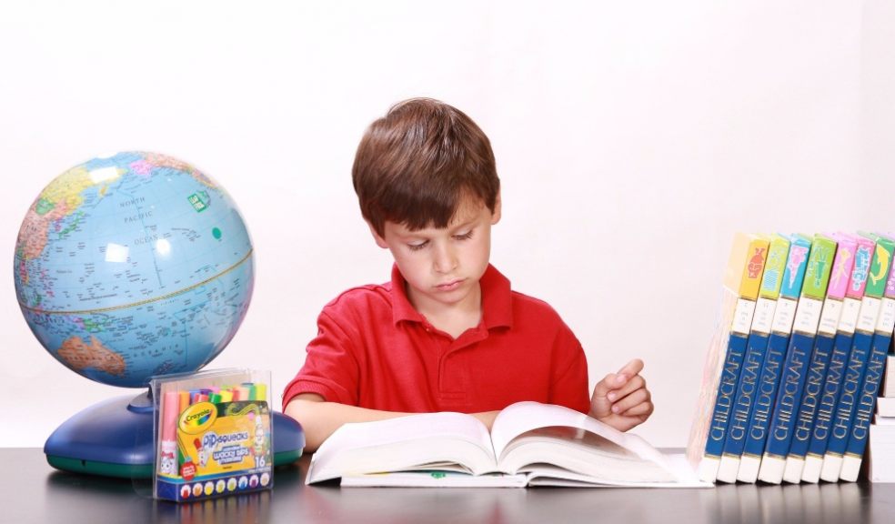 Boy being home educated at desk with globe and educational books