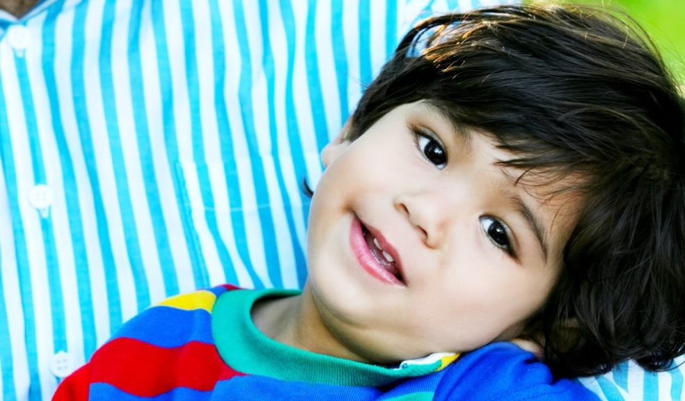 Happy toddler with cerebral palsy in his father's arms