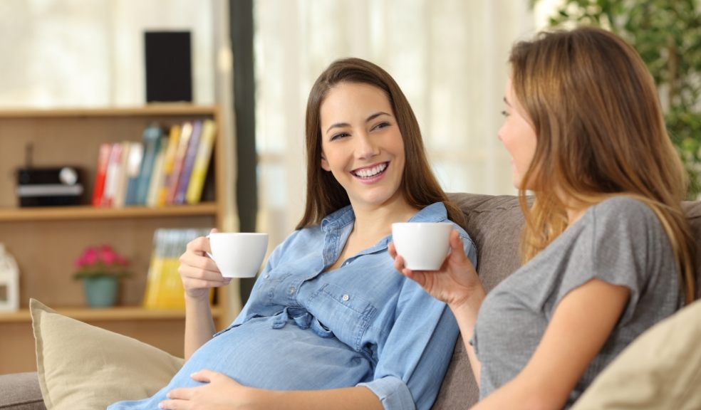  Pregnant woman talking with a friend at home