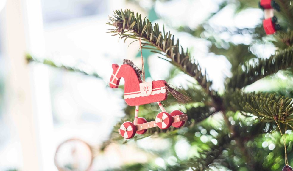 Wooden horse Christmas bauble on tree branch 