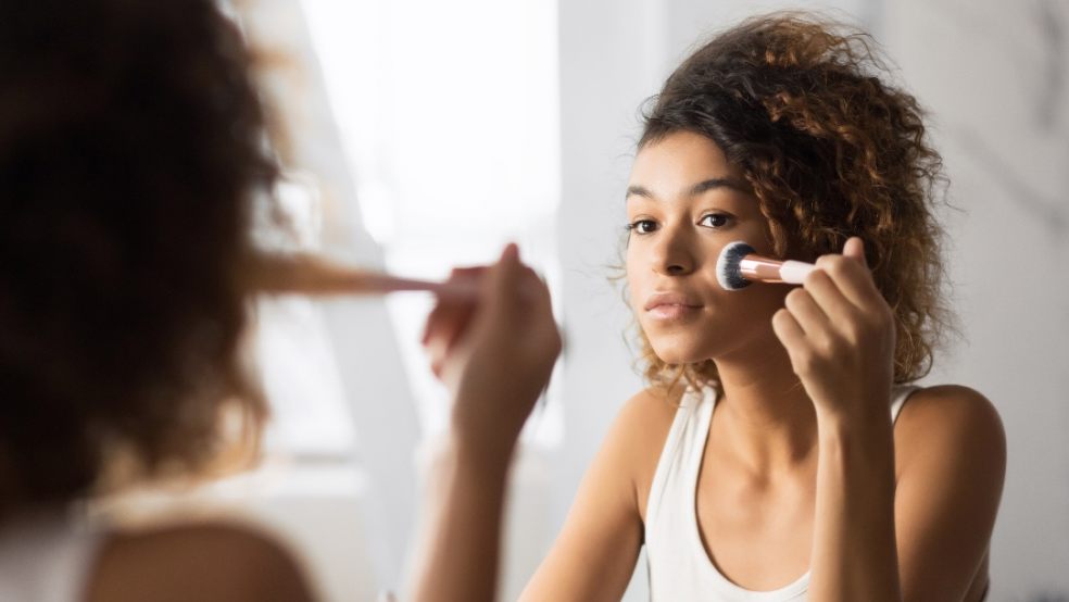 lady in mirror applying makeup