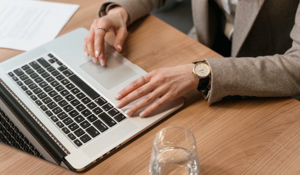 A woman in a business suit types on her laptop, focused on understanding how the fax API works.
