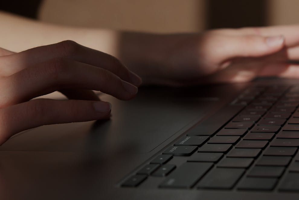 A person working on a laptop, focusing on Fax API security protocols and compliance standards.