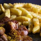 A photograph showing currywurst and fries