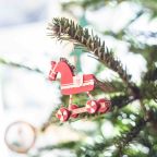 Wooden horse Christmas bauble on tree branch 