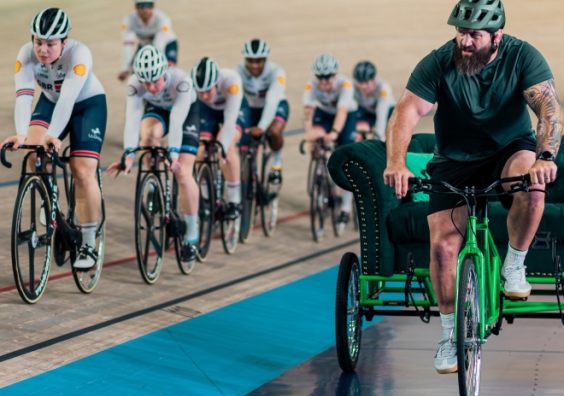 A man on a trike watches cyclists in a velodrome 