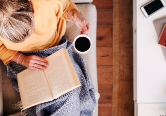 Woman reading book on sofa with a cup of coffee. Getty Images/iStockphoto Woman reading book on sofa with a cup of coffee. Getty Images/iStockphoto