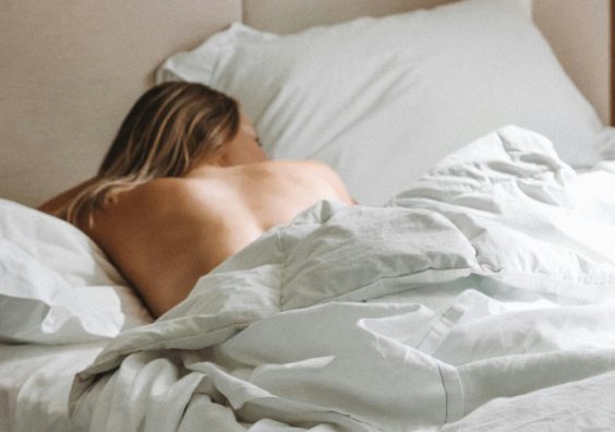 A woman half naked in bed