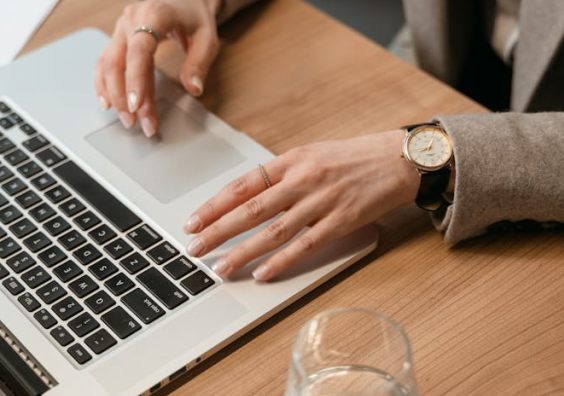 A woman in a business suit types on her laptop, focused on understanding how the fax API works.