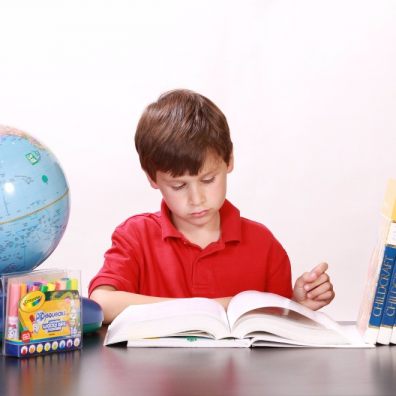 Boy being home educated at desk with globe and educational books