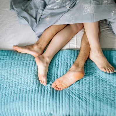 The legs of a couple in bed together