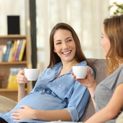  Pregnant woman talking with a friend at home