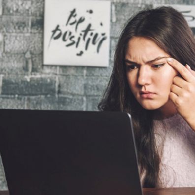 Teen girl squinting whilst looking at computer screen