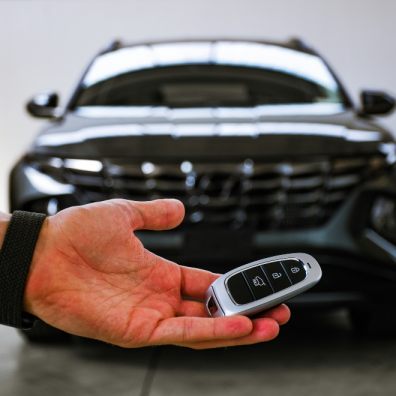 A man holding a key in front of a new car