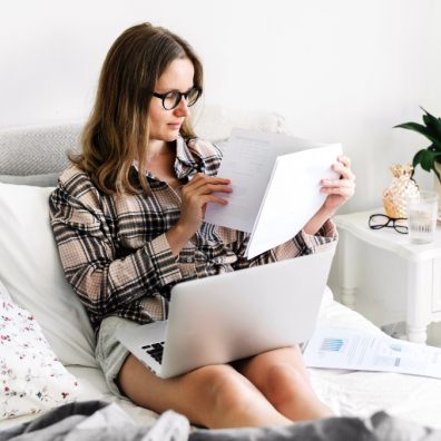 Woman working at home on laptop in bedroom. Lifestyle