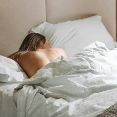 A woman half naked in bed