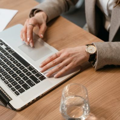 A woman in a business suit types on her laptop, focused on understanding how the fax API works.